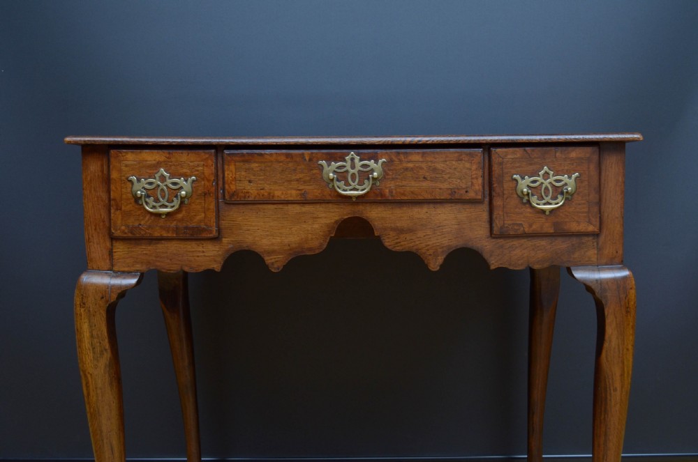 An 18th-century George II oak lowboy table featuring three drawers with decorative brass handles, a shaped lower apron, and four cabriole legs with pad feet. View VI