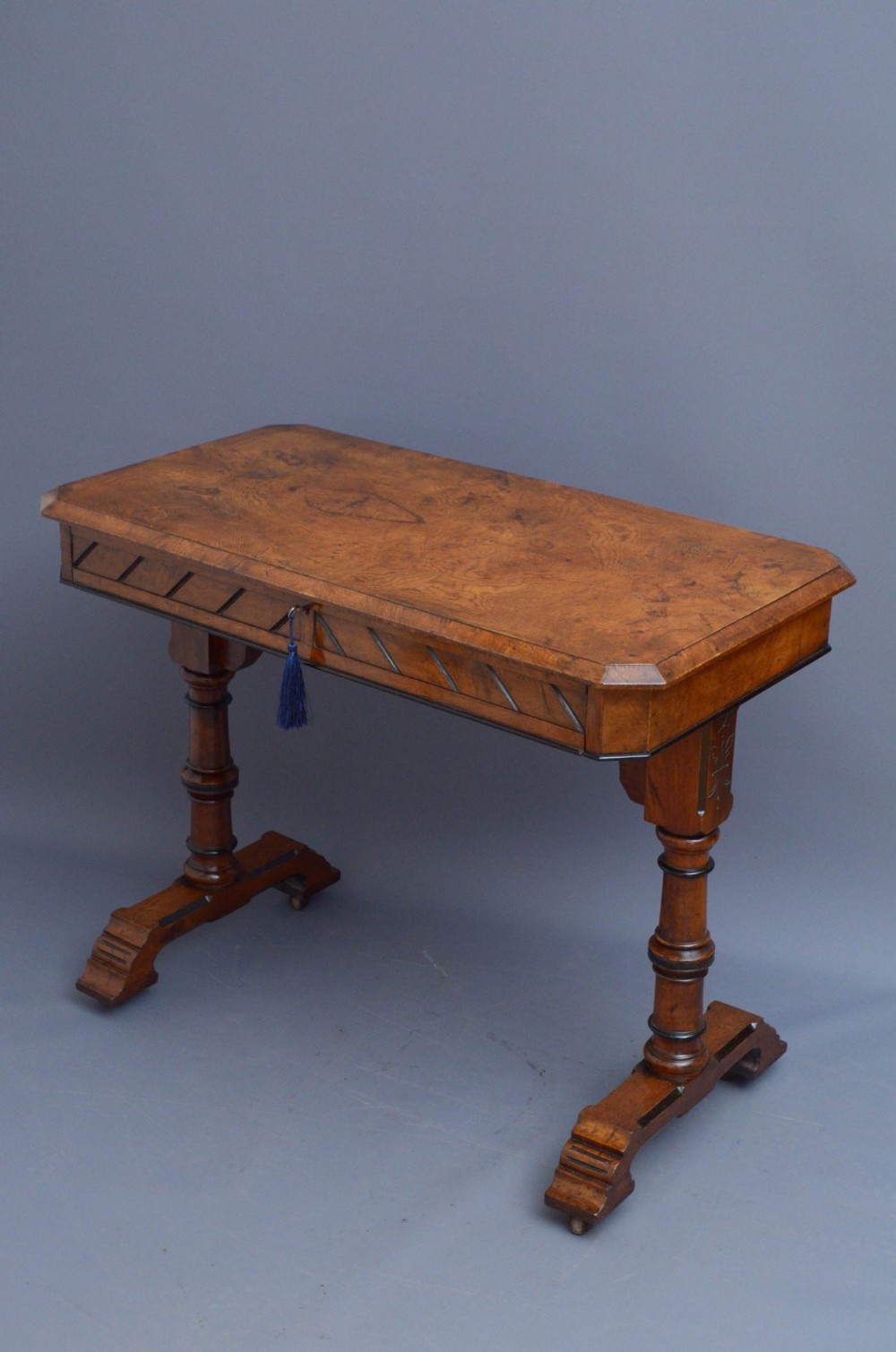 An Aesthetic Movement pollard oak side table featuring a figured timber top, a single drawer with ebonised geometric incised decoration, turned twin supports, and splayed legs on castors.