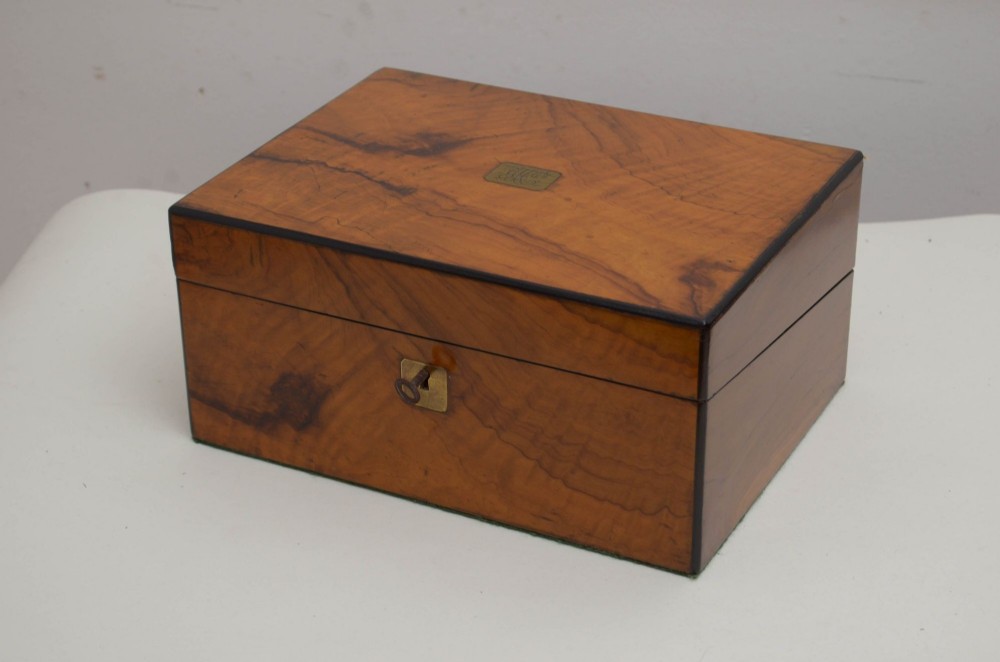 A Victorian rectangular writing slope crafted from figured brown walnut wood with a central brass cartouche and keyhole escutcheon.