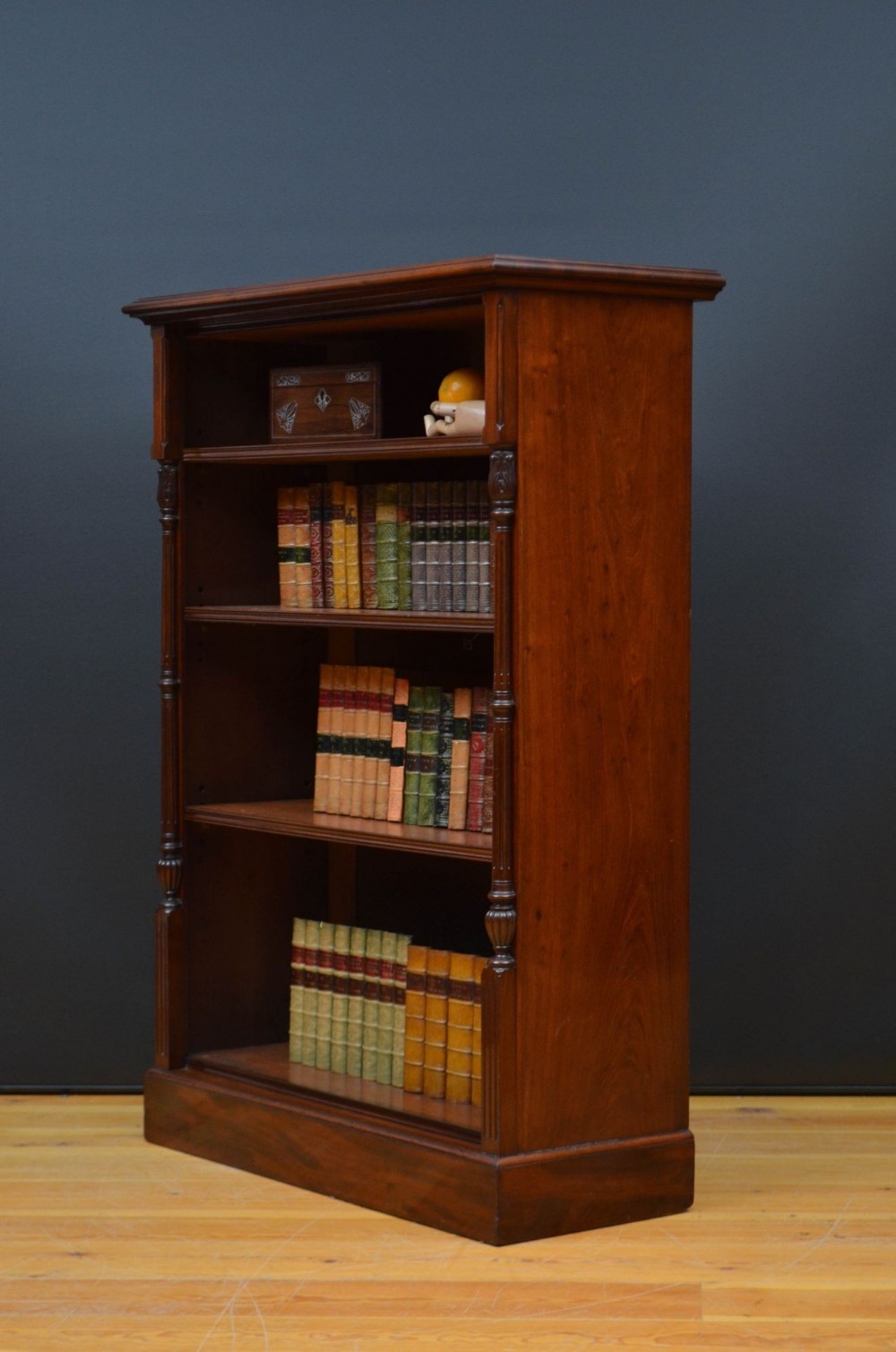 A Victorian mahogany open bookcase featuring four open shelves flanked by turned pilasters resting on a solid plinth base.