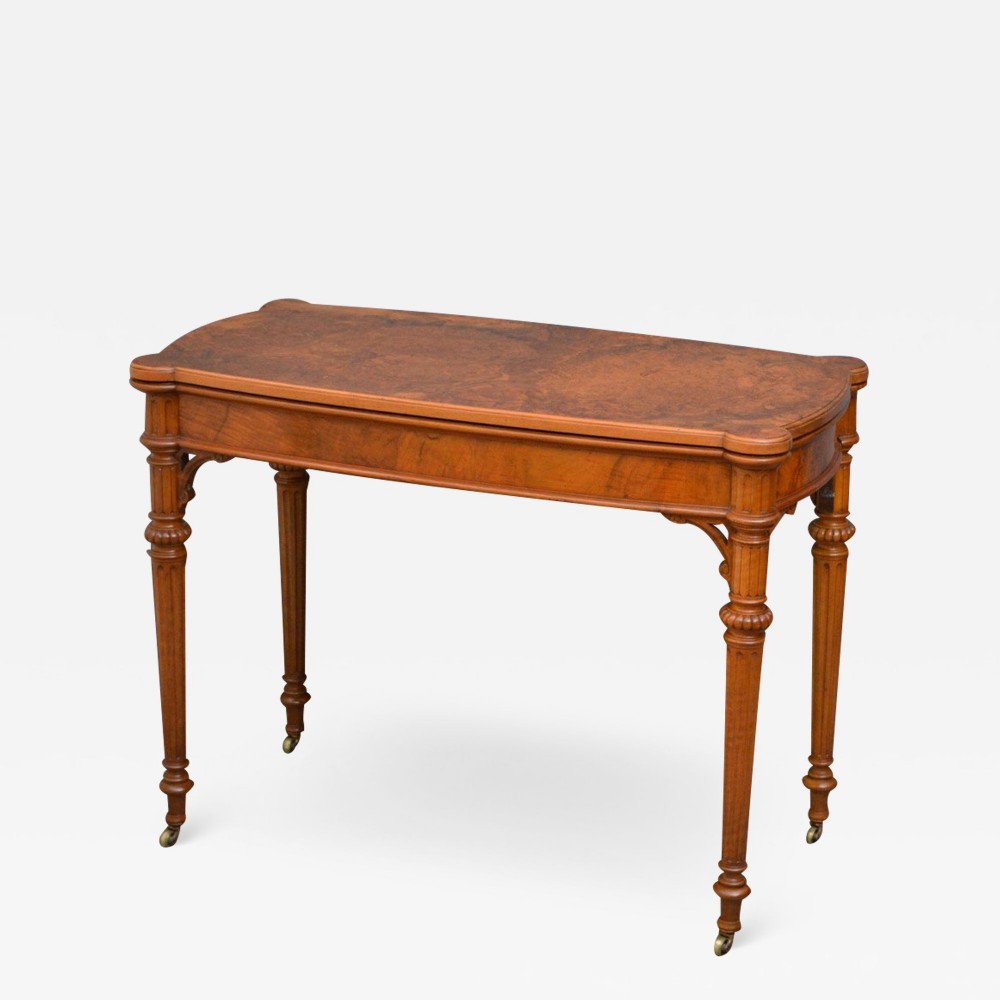 A Victorian burr walnut table with a polished figured top, reeded turned legs, and brass castors.