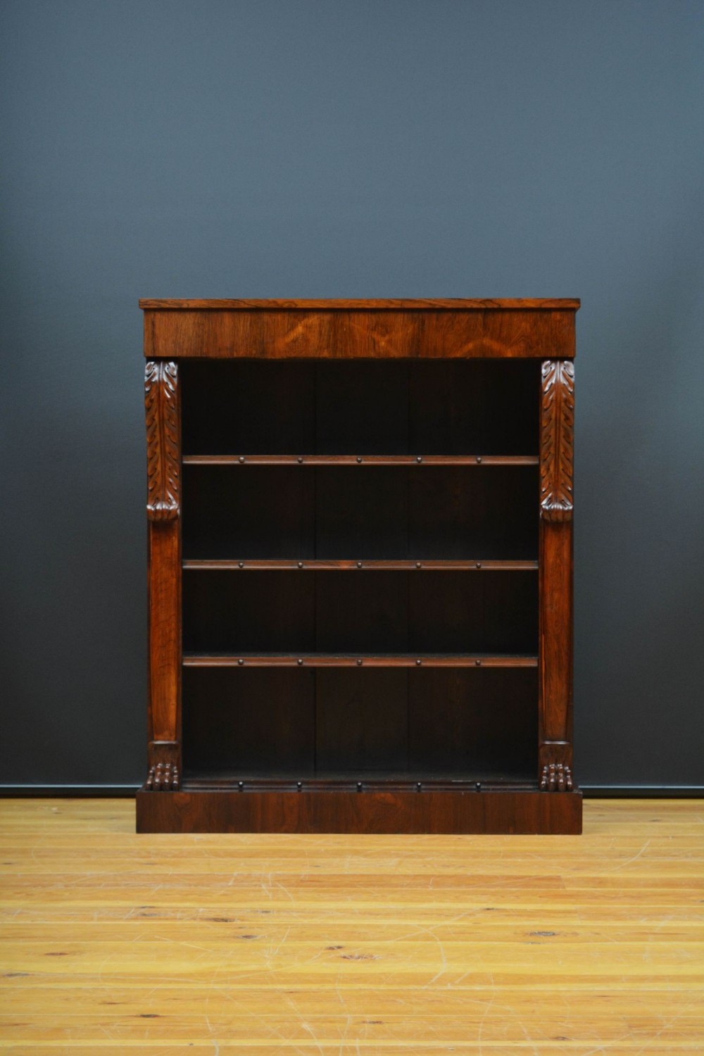 A William IV open bookcase in dark rosewood featuring carved acanthus pilasters and adjustable shelves.