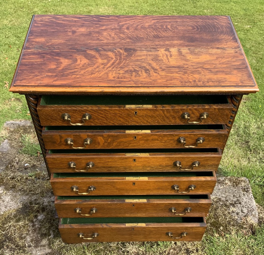 A late Victorian oak tall chest featuring six drawers flanked by barley twist columns resting on turned legs with a open bottom shelf. View VII