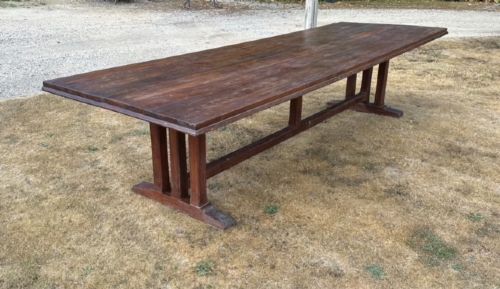 A long rectangular dark walnut refectory dining table featuring end trestle supports joined by a central lower stretcher rail. View II