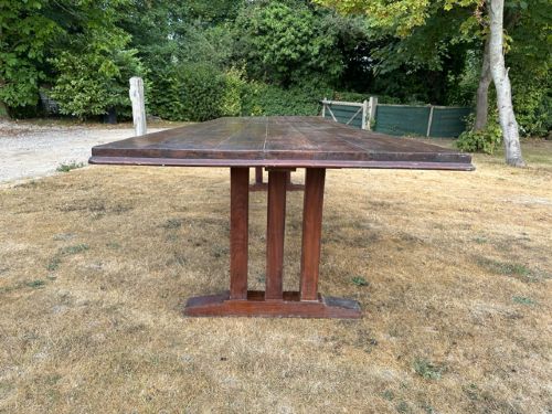 A long rectangular dark walnut refectory dining table featuring end trestle supports joined by a central lower stretcher rail. View III