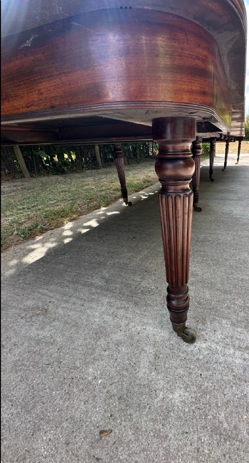 A long mahogany extending dining table with turned fluted legs and brass castors. View VI