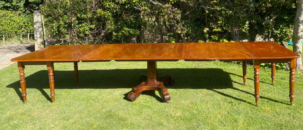 An exceptionally long Early Victorian mahogany extending dining table with turned legs, central pedestal base on scroll feet, and brass castors.