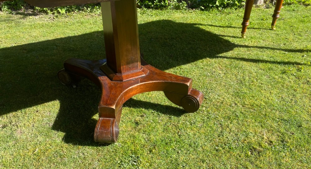 An exceptionally long Early Victorian mahogany extending dining table with turned legs, central pedestal base on scroll feet, and brass castors. View III