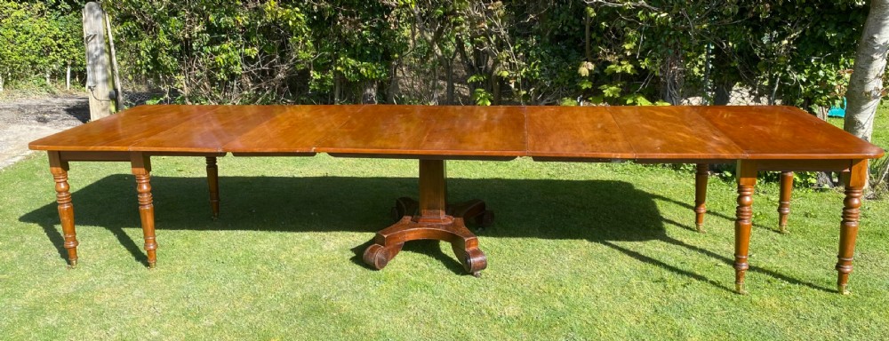 An exceptionally long Early Victorian mahogany extending dining table with turned legs, central pedestal base on scroll feet, and brass castors. View VI