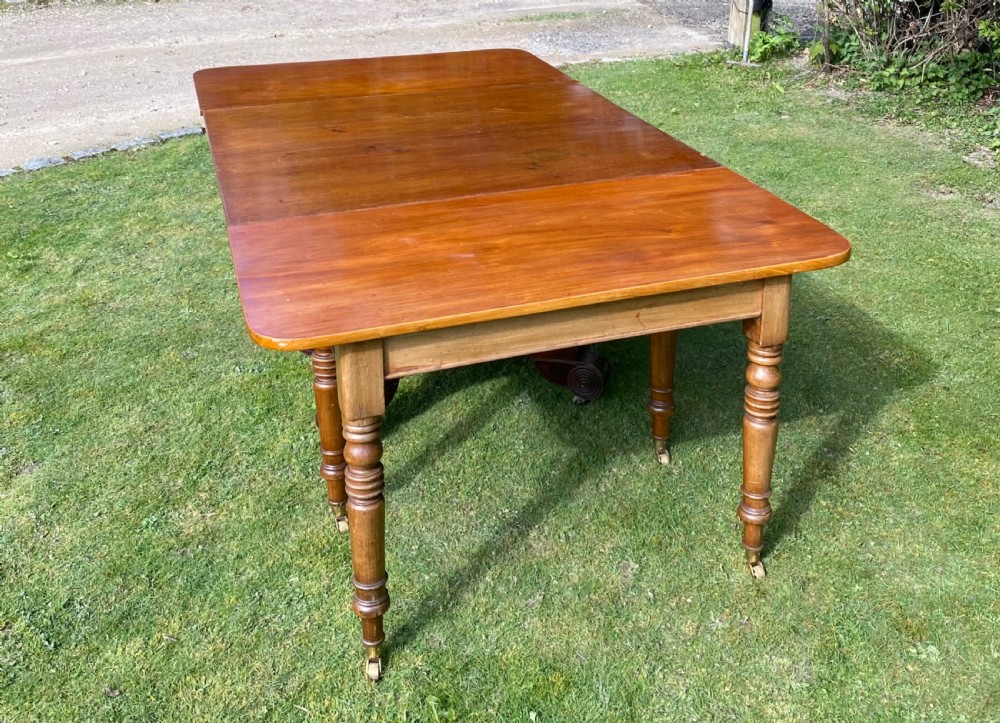 An exceptionally long Early Victorian mahogany extending dining table with turned legs, central pedestal base on scroll feet, and brass castors. View X
