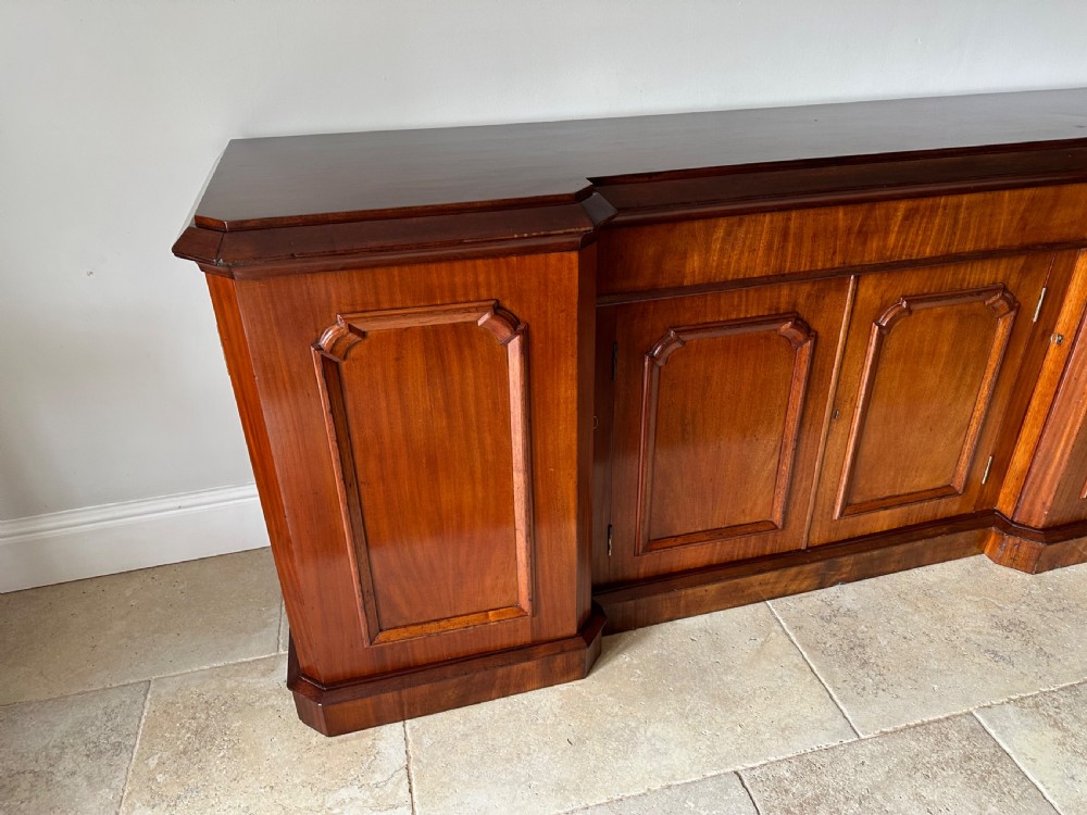 A nineteenth-century Victorian mahogany breakfront sideboard featuring four moulded panel doors and a polished wooden top. View X
