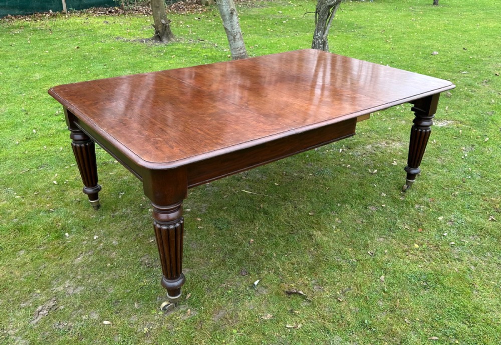 A rectangular mahogany extending dining table from the William IV period with fluted turned legs and brass castors. View VIII