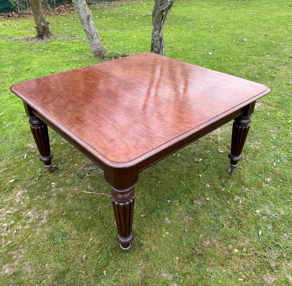 A rectangular mahogany extending dining table from the William IV period with fluted turned legs and brass castors. View X