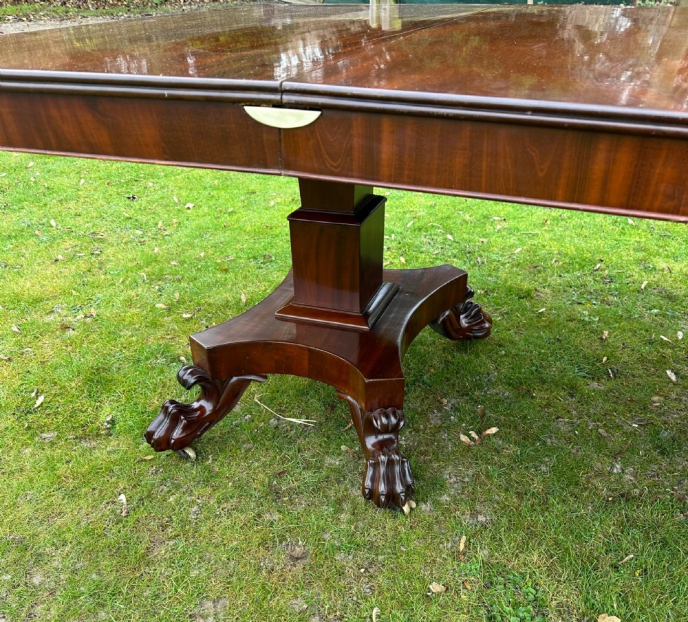 A Regency mahogany twin-pillar extending dining table featuring a polished rectangular top with rounded corners and carved claw-foot pedestal bases. View III