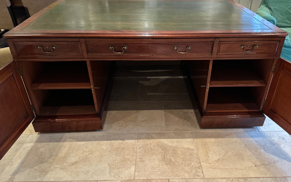 A Victorian mahogany partners desk with a green leather inset writing surface, brass drop handles, and dual pedestal bases. View V