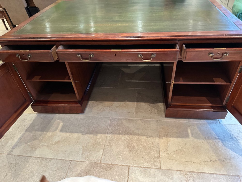 A Victorian mahogany partners desk with a green leather inset writing surface, brass drop handles, and dual pedestal bases. View VIII