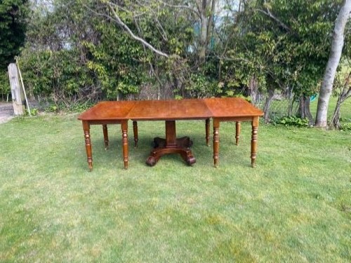 An exceptionally long Early Victorian mahogany extending dining table with turned legs, central pedestal base on scroll feet, and brass castors. View IX