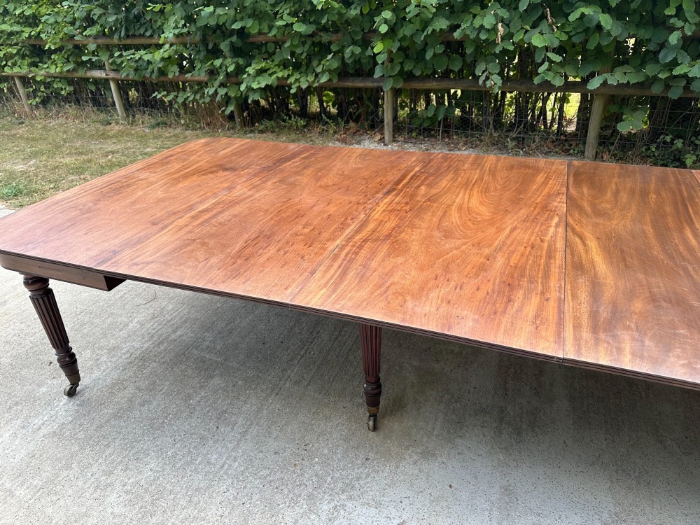 A long mahogany extending dining table with turned fluted legs and brass castors. View V