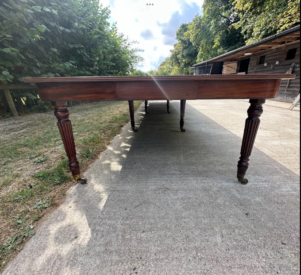 A long mahogany extending dining table with turned fluted legs and brass castors. View VII