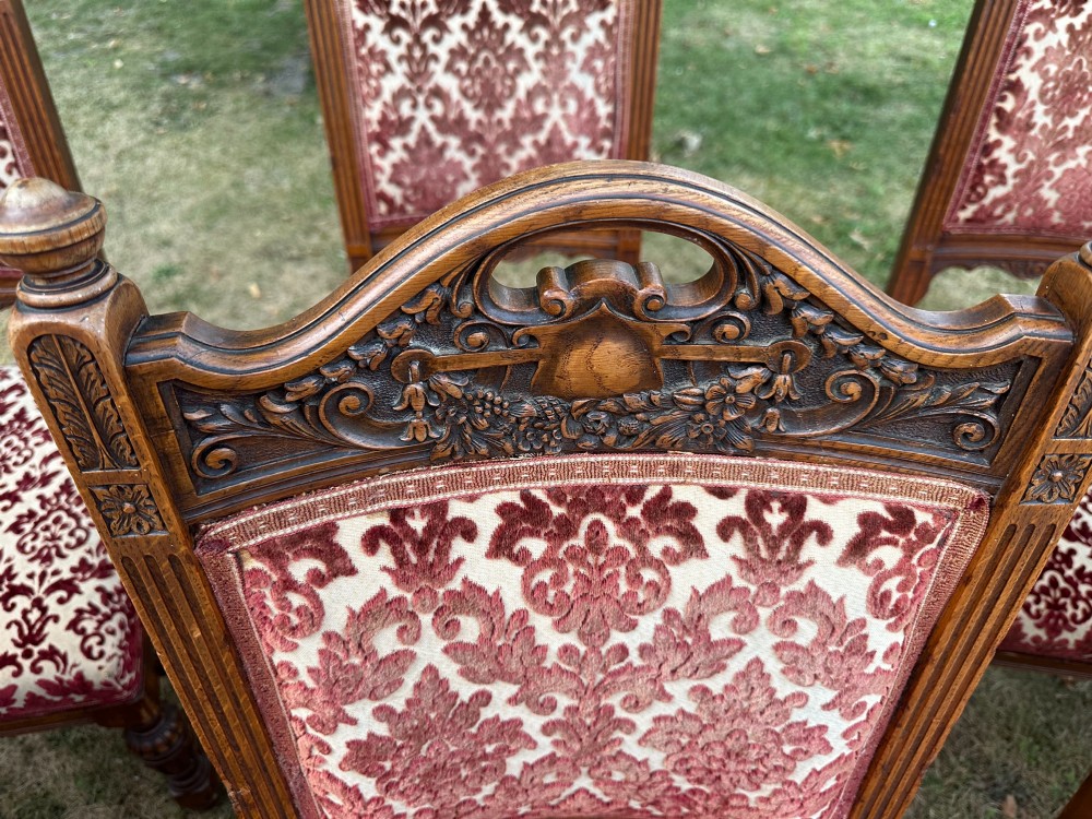 A set of ten Edwardian oak dining chairs featuring carved top rails, turned legs, and burgundy patterned velvet upholstery. View II