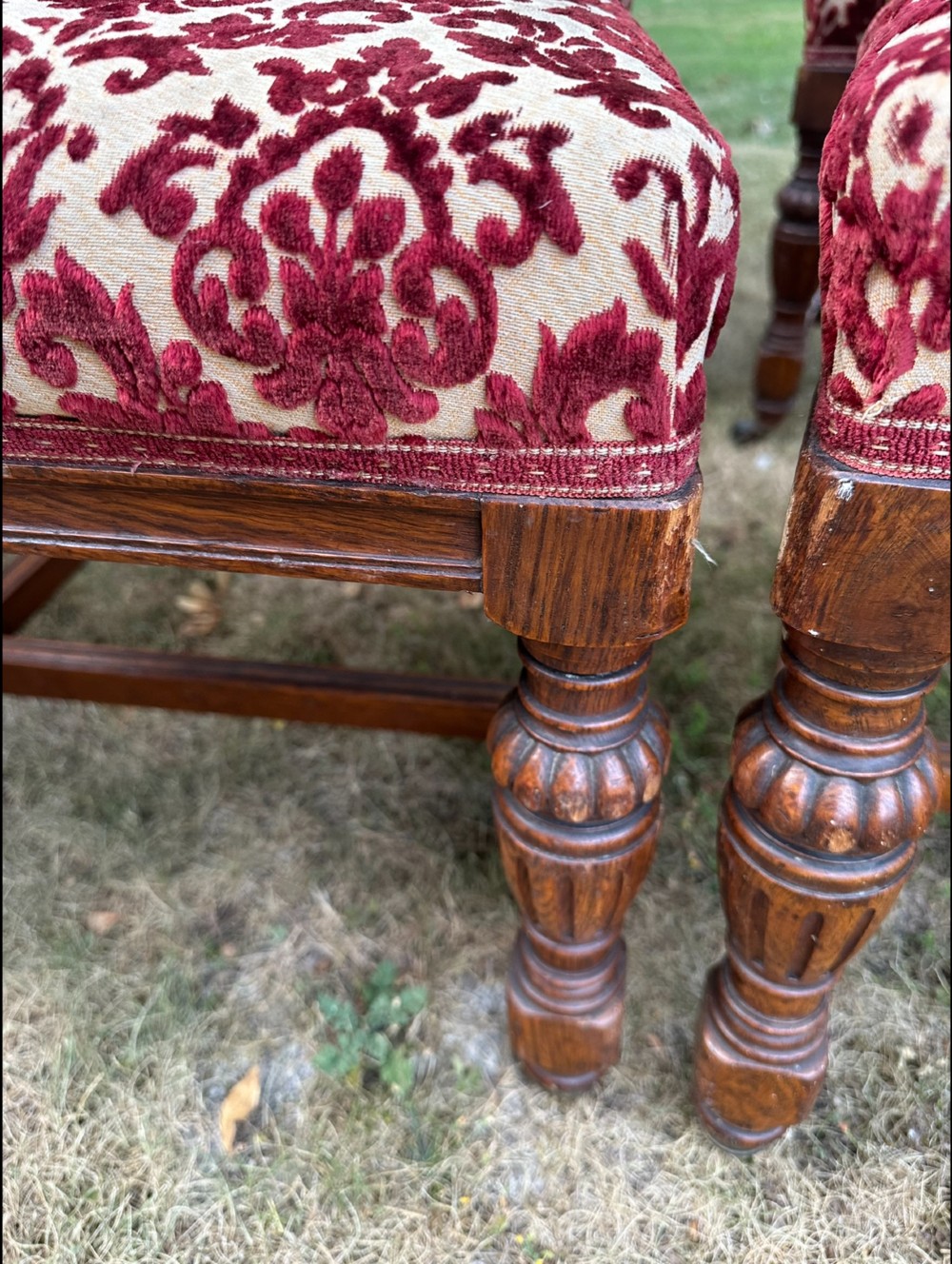 A set of ten Edwardian oak dining chairs featuring carved top rails, turned legs, and burgundy patterned velvet upholstery. View V