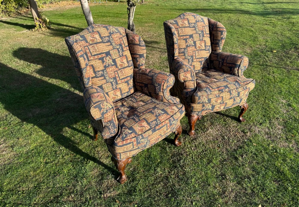 A pair of 1920s wingback armchairs upholstered in a gold and blue manuscript patterned tapestry fabric with carved wooden cabriole front legs. View II
