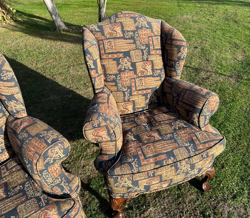A pair of 1920s wingback armchairs upholstered in a gold and blue manuscript patterned tapestry fabric with carved wooden cabriole front legs. View III