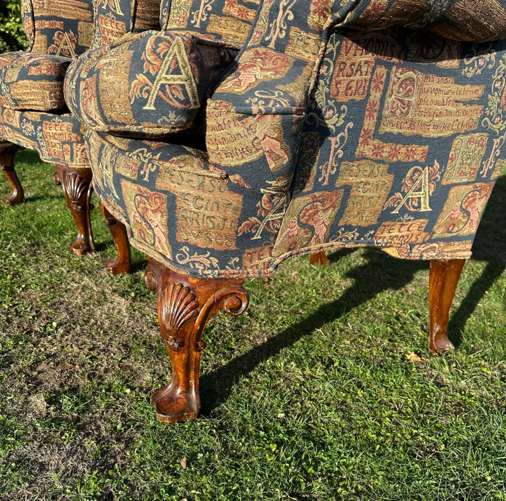 A pair of 1920s wingback armchairs upholstered in a gold and blue manuscript patterned tapestry fabric with carved wooden cabriole front legs. View IV