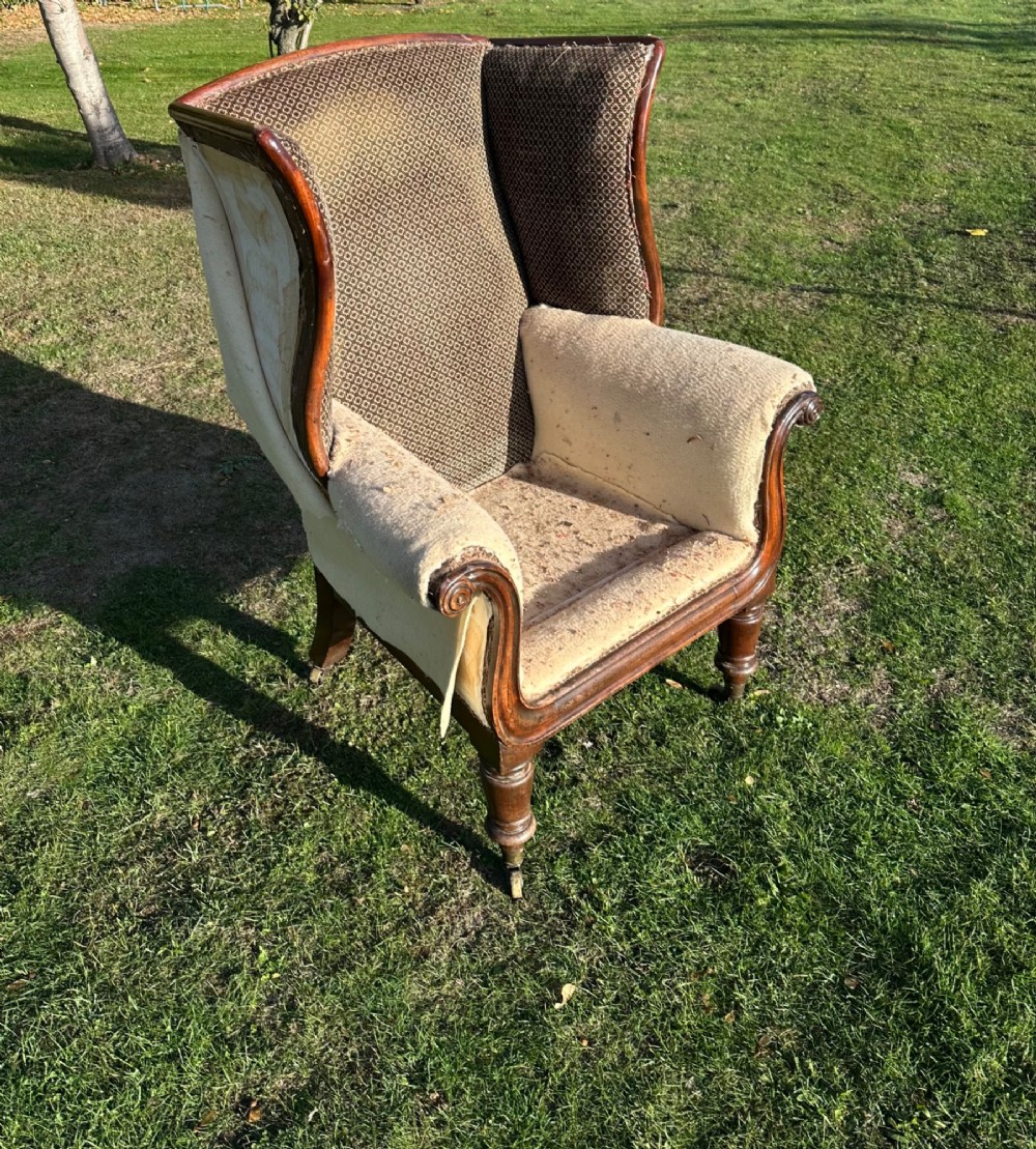 A William IV mahogany wingback armchair featuring patterned fabric on the backrest, scrolled arms, and turned front legs on brass castors. View II