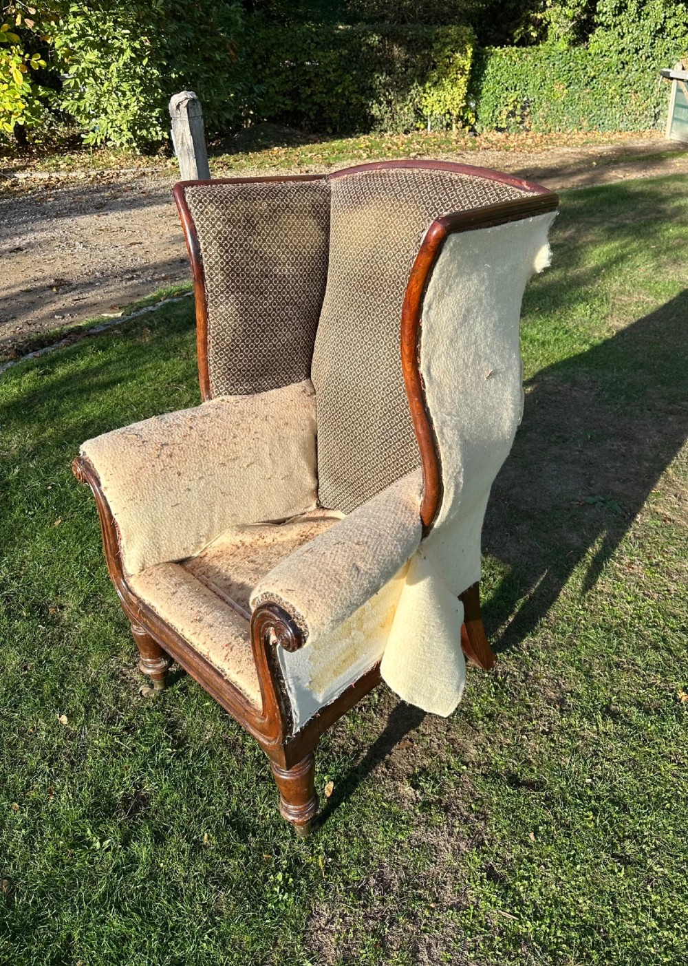 A William IV mahogany wingback armchair featuring patterned fabric on the backrest, scrolled arms, and turned front legs on brass castors. View III