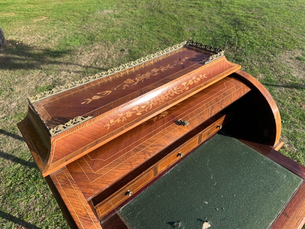 A 19th-century French cylinder roll-top desk crafted with floral marquetry inlays, slender cabriole legs, and brass ormolu mounts. View V
