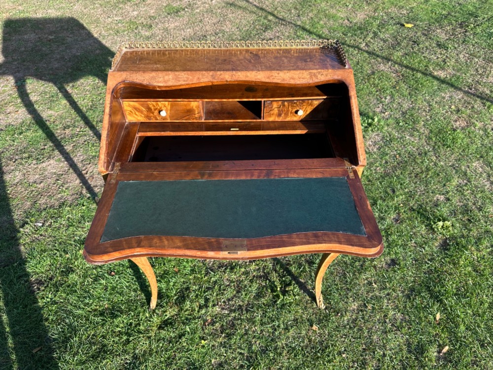 A 19th-century French bureau de dame crafted with floral marquetry inlay, slender cabriole legs, decorative brass corner mounts, and a brass gallery along the top. View IV
