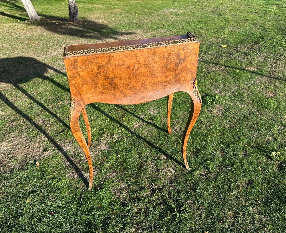 A 19th-century French bureau de dame crafted with floral marquetry inlay, slender cabriole legs, decorative brass corner mounts, and a brass gallery along the top. View V