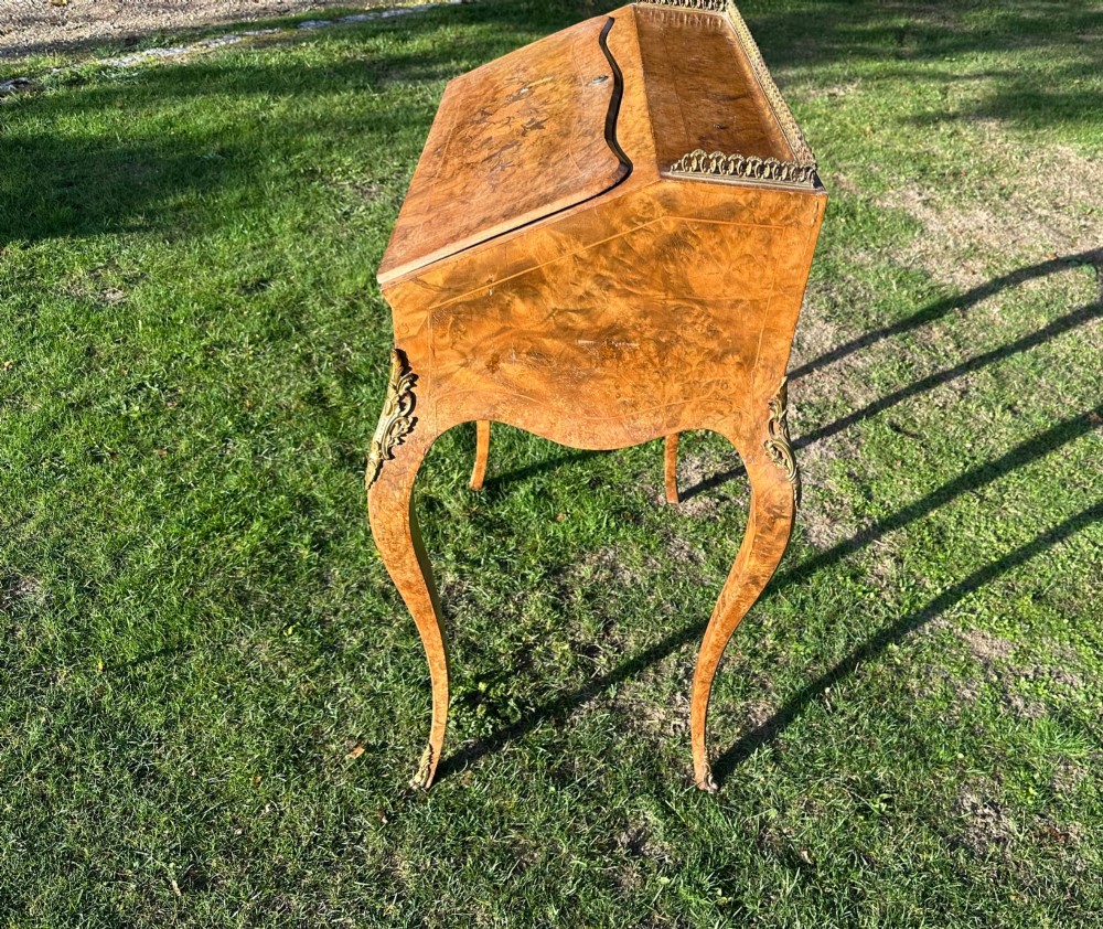 A 19th-century French bureau de dame crafted with floral marquetry inlay, slender cabriole legs, decorative brass corner mounts, and a brass gallery along the top. View VI