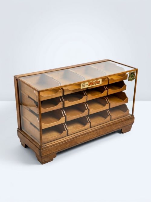 fig 1. A 1920s oak haberdashery cabinet featuring sixteen drawers arranged in a four-by-four grid with dark metal cup handles.