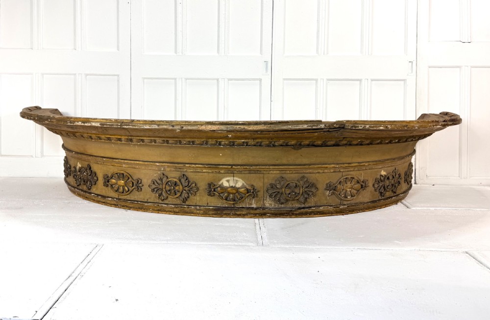 A large curved 19th-century carved timber and gilded window pelmet decorated with floral rosettes and egg-and-dart moulding.