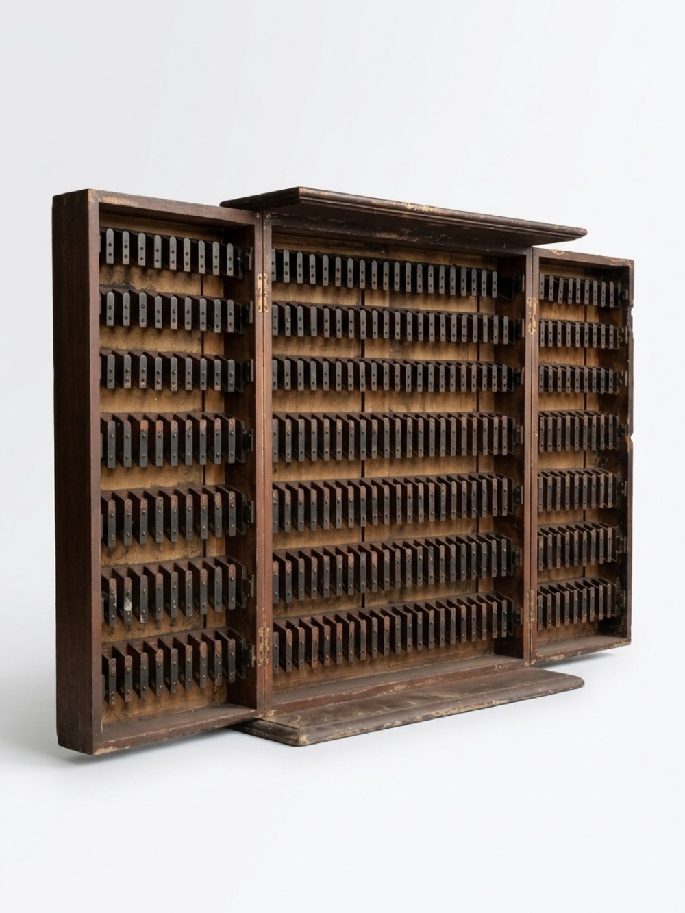 A nineteenth-century dark brown wooden railway ticket cupboard with hinged folding doors revealing dozens of small vertical slot compartments.