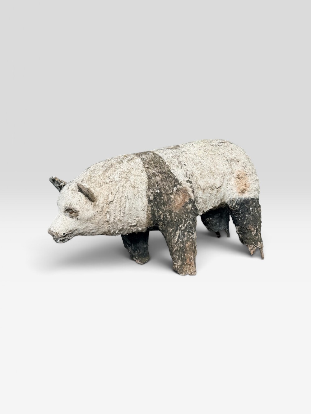 A large, textured cast stone sculpture of a standing panda bear featuring weathered off-white and dark charcoal markings.
