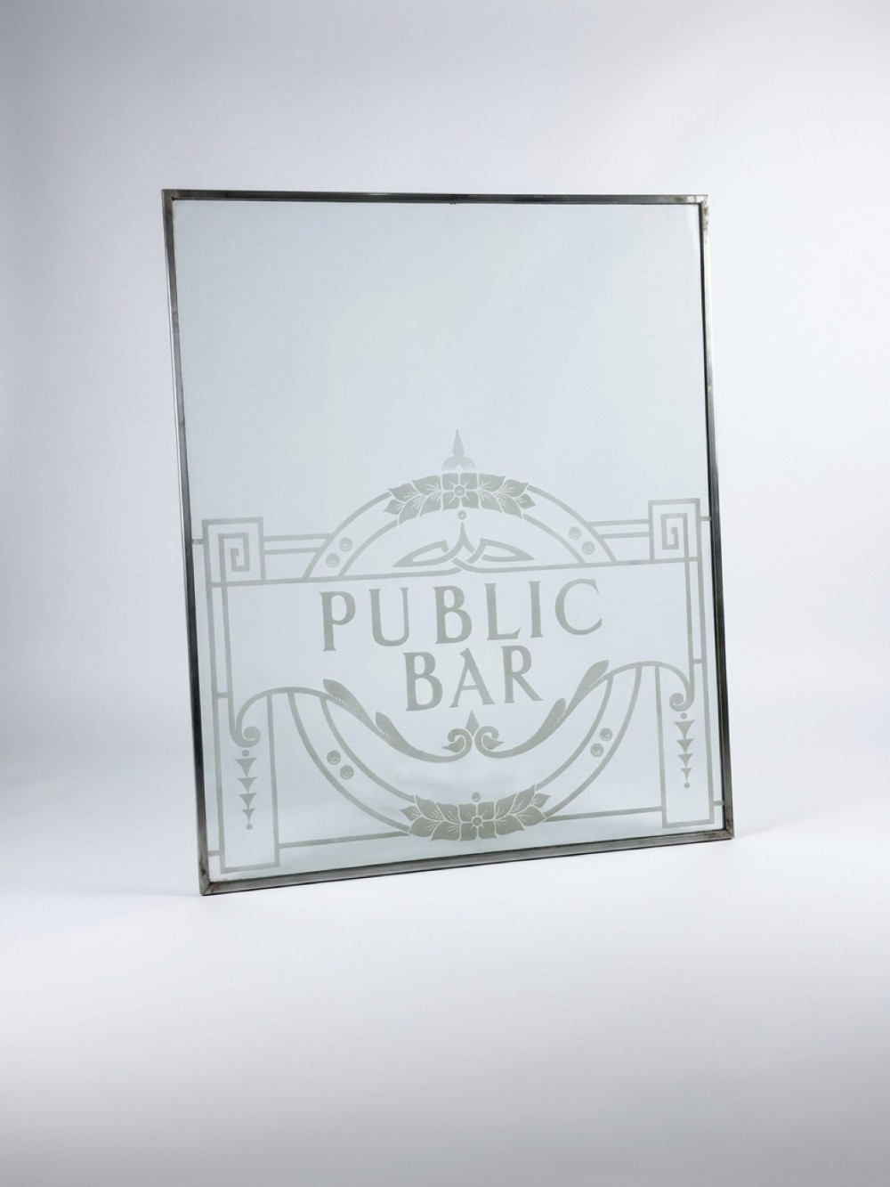 A rectangular clear glass panel with acid-etched decorative detailing and central text reading PUBLIC BAR set within a slim metal frame.