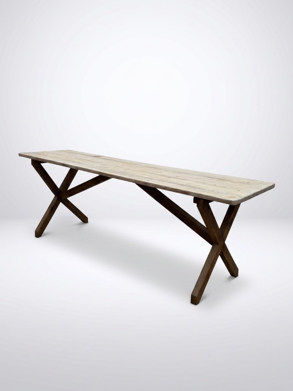 An English 1900s pine dining table featuring a long plank top supported by dark cross-leg trestle bases and a central stretcher.