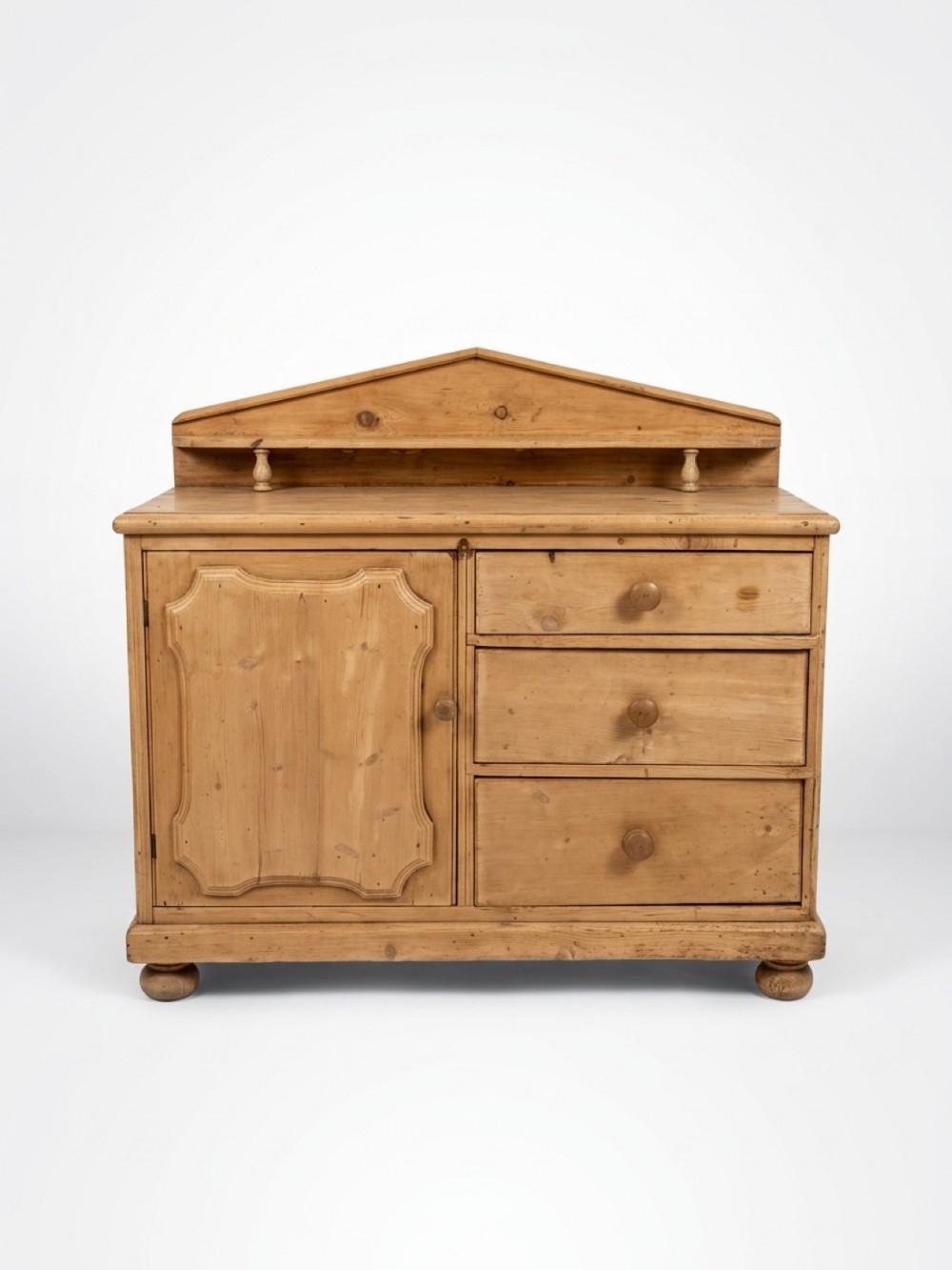 A nineteenth-century pitch pine chiffonier featuring a triangular pediment top with a raised shelf, three drawers on the right, and a moulded cupboard door on the left.