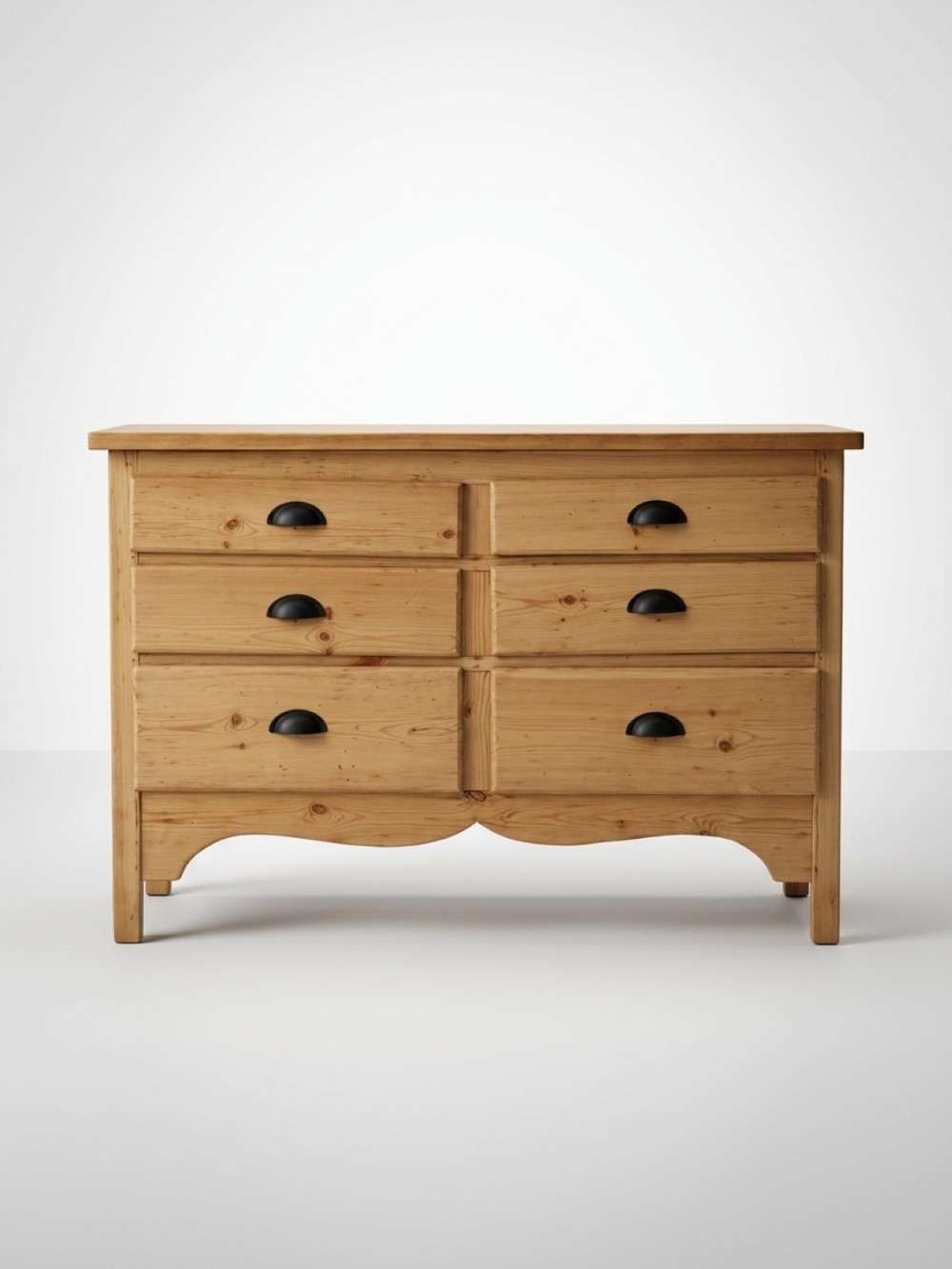 A nineteenth-century pine chest featuring six drawers arranged in two columns with dark cup handles and a scalloped apron base.