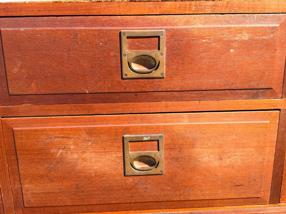 A low-profile mahogany bank of six drawers featuring brass label handles set into a moulded frame with a plinth base. View II