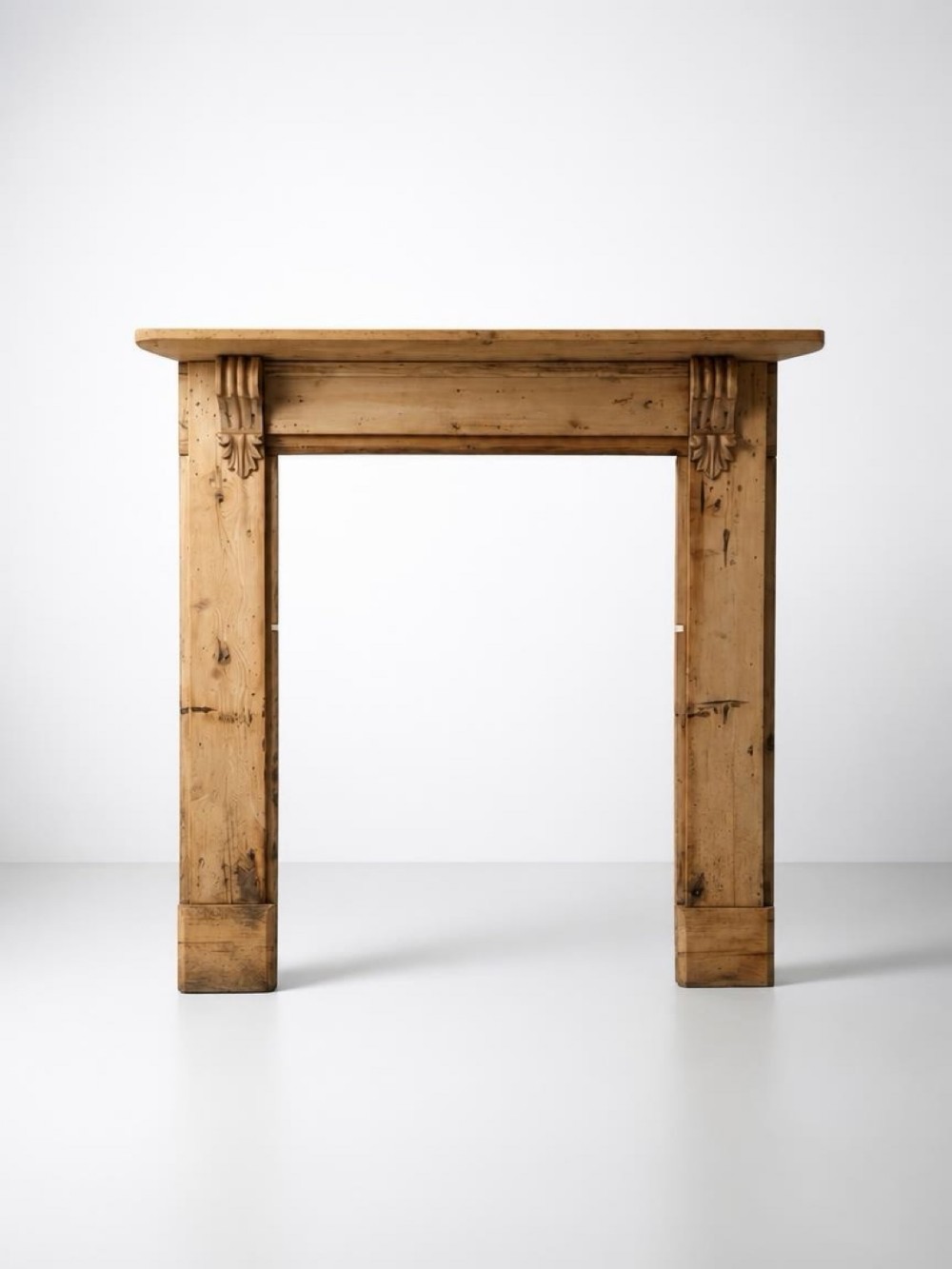 A nineteenth-century pitch pine fire surround featuring carved acanthus leaf corbels beneath a moulded mantel shelf.