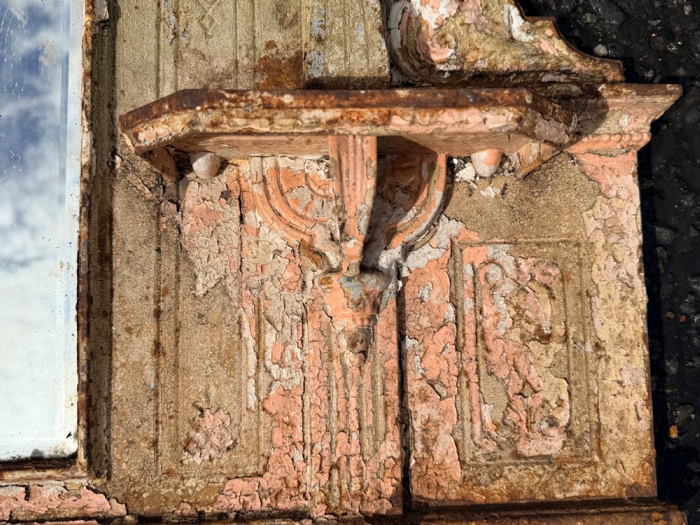 A 19th-century cast iron architectural wall mirror featuring a pointed pediment, decorative finials, side shelves, and a weathered paint finish. View II