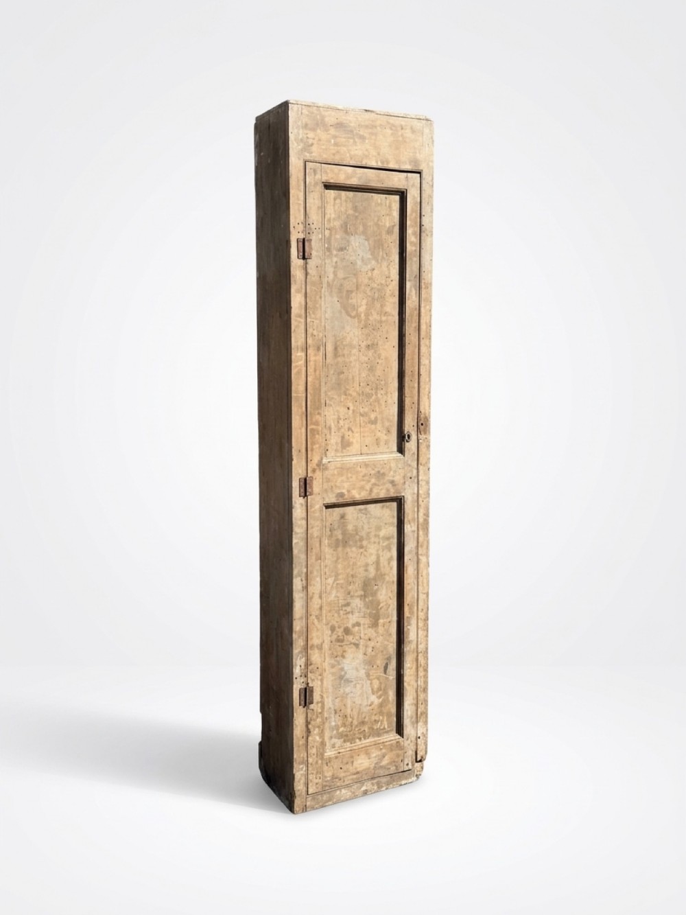 A tall, narrow Georgian pine gun cupboard featuring a single door with two panel inserts and visible iron hinges.