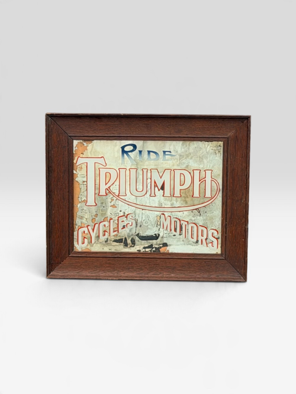 A rectangular 1920s Triumph Cycles and Motors advertising mirror featuring foxed glass and a dark oak timber frame.
