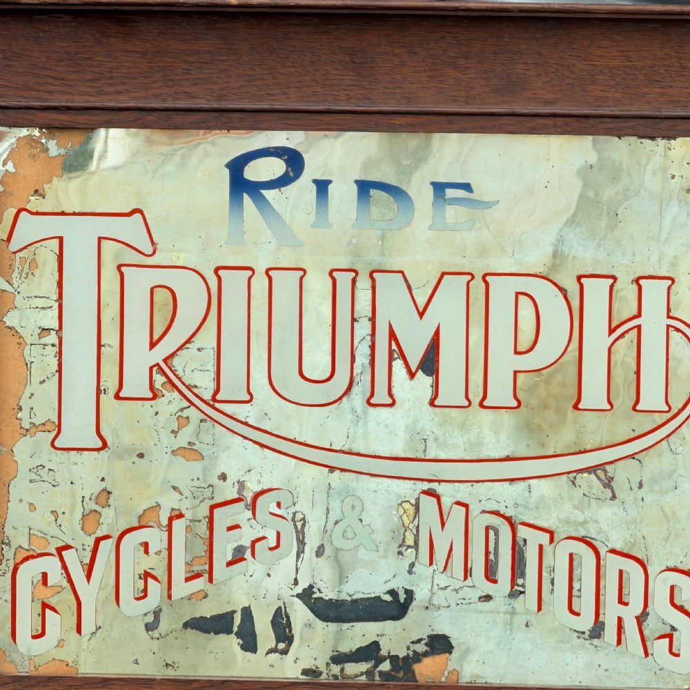 A rectangular 1920s Triumph Cycles and Motors advertising mirror featuring foxed glass and a dark oak timber frame. View V