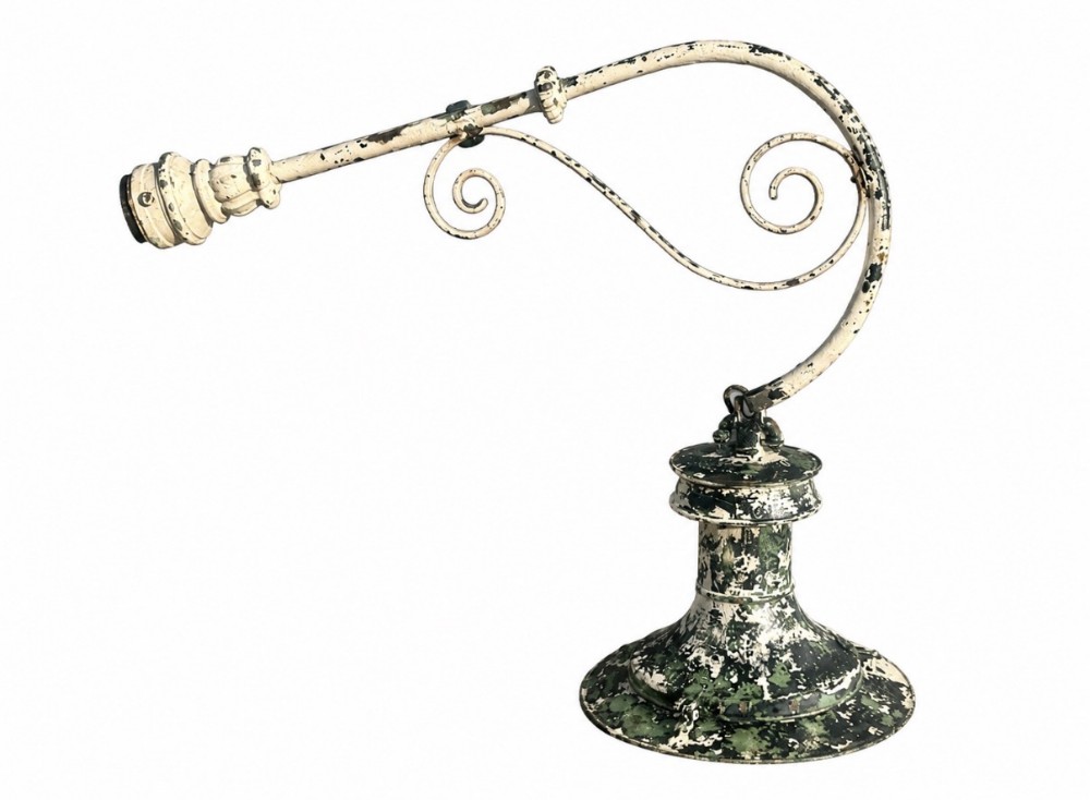 A 19th-century painted metal lantern bracket with decorative scrollwork and a distressed white and green finish.
