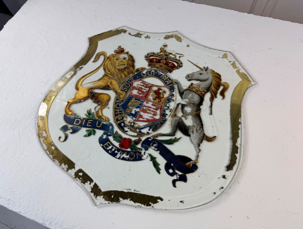 An Edwardian heraldic shield-shaped plaque featuring the gilded British Royal Coat of Arms with a lion, unicorn, and mottoes against a painted off-white background with distressed gold trim. View IV